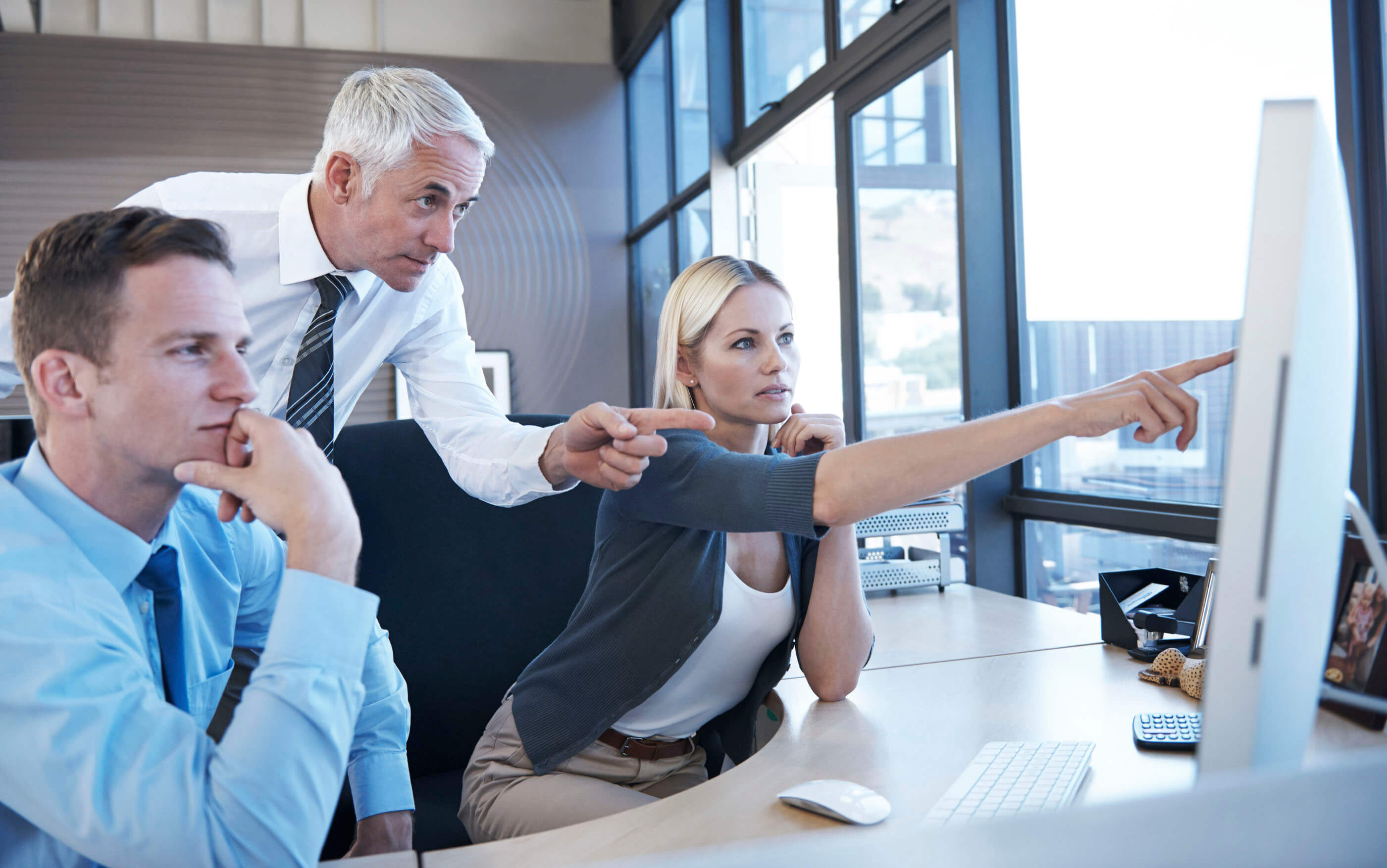 A business team pointing at a website on a computer screen